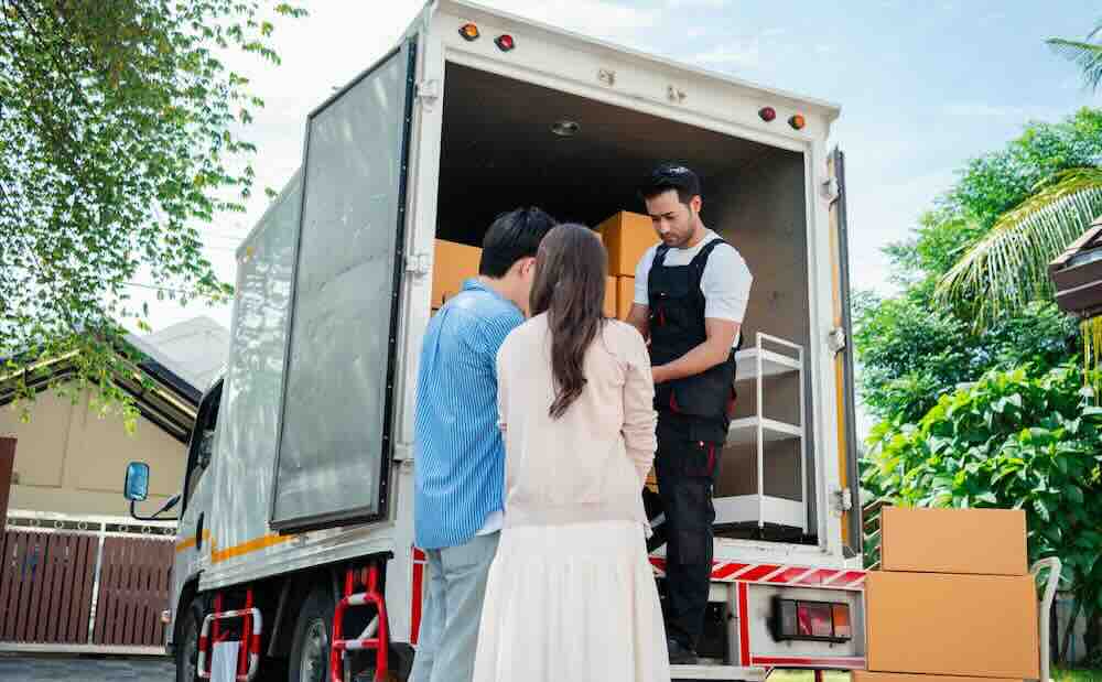 Couple standing in front of a moving van waiting to pay for movers.