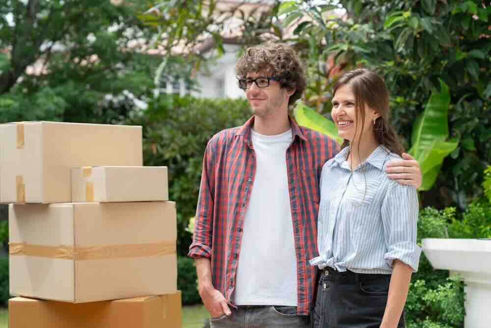 Happy man in a plaid shirt and woman in blue who understand when to pay movers.