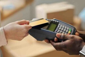 Closeup of a hand holding a credit card with a card machine, representing when to pay movers without a moving company deposit.