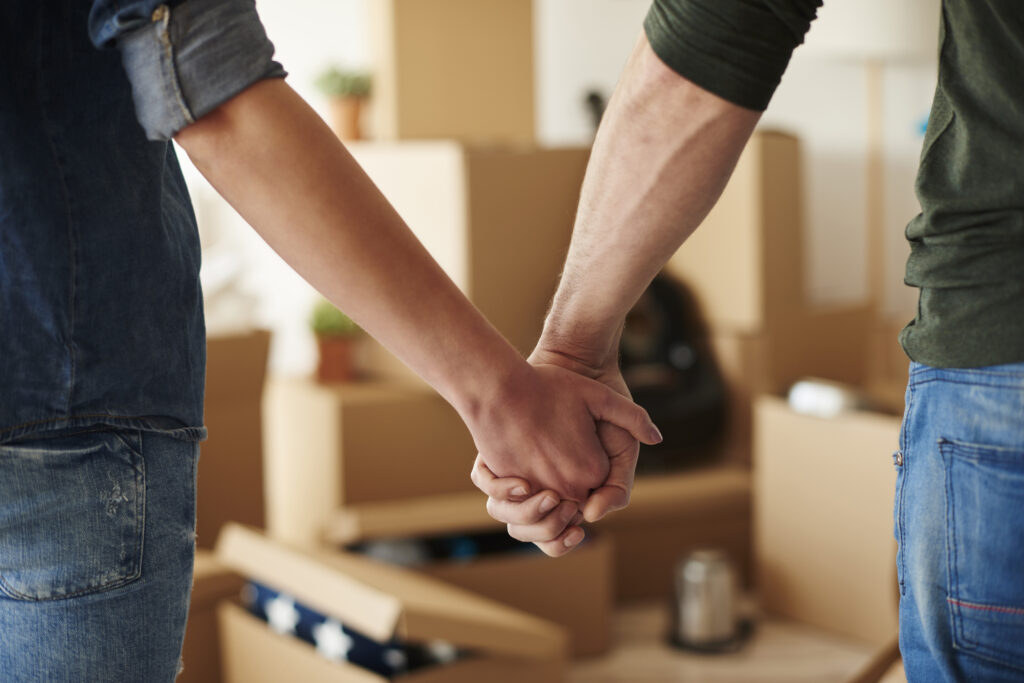 Couple holding hands in front of boxes after working with small-scale moving services.