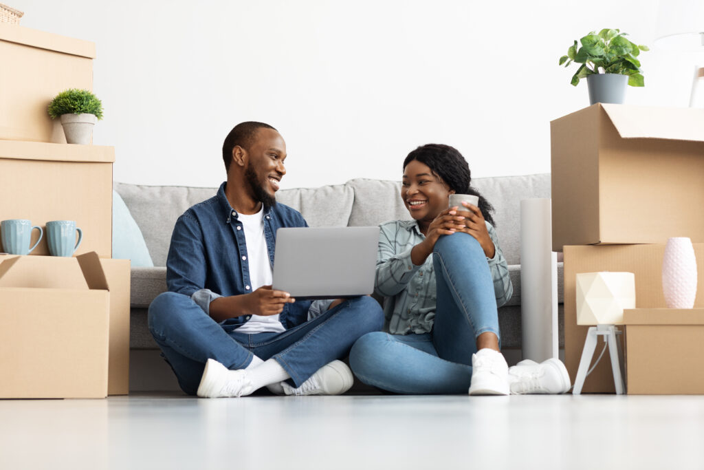 Happy African American couple seated on the floor with boxes representing micro moves and short-distance relocation trends.
