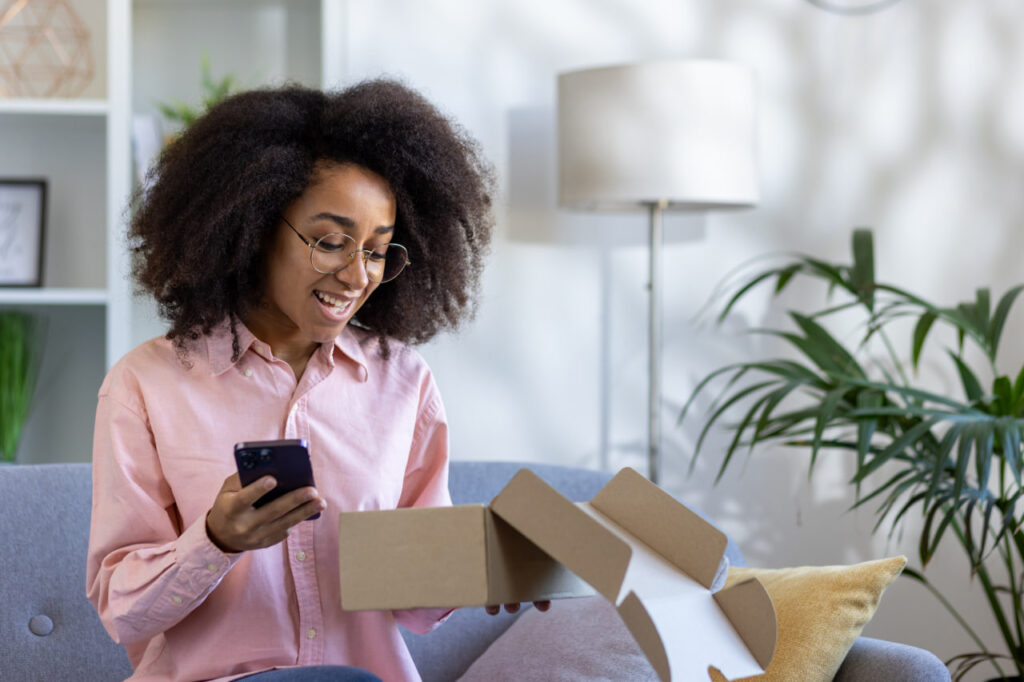 Happy woman opening moving subscription boxes from a moving kit delivery service.