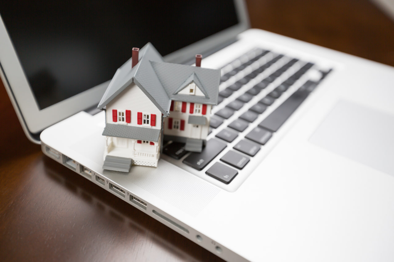 Toy house on a keyboard representing online apartment hunting tips with a virtual apartment tour checklist.