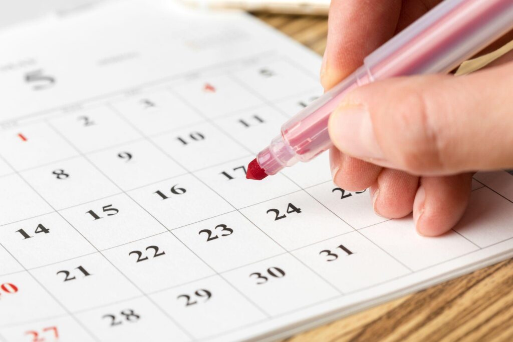 Close up of a hand writing on a calendar with a red market after booking early with cost-effective moving strategies.