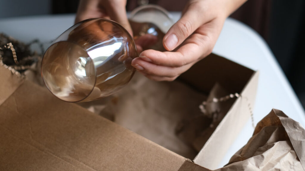 An antique movers hand using specialty packing techniques to protect fancy glassware.